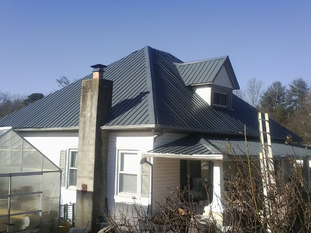 Dark blue standing seam metal roof on a white farmhouse with dormer — Slate & Tile Roof Repair by Roofing Brothers in Bellingham