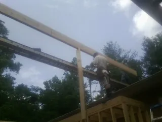 Carpenter setting a ridge beam over a new addition frame — Ice Dam Removal by Roofing Brothers in Bellingham