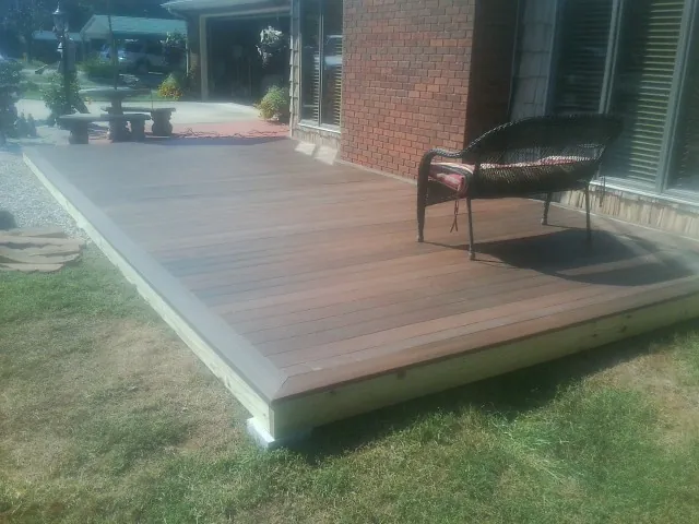New wood deck and wicker chair beside a brick house in Bellingham
