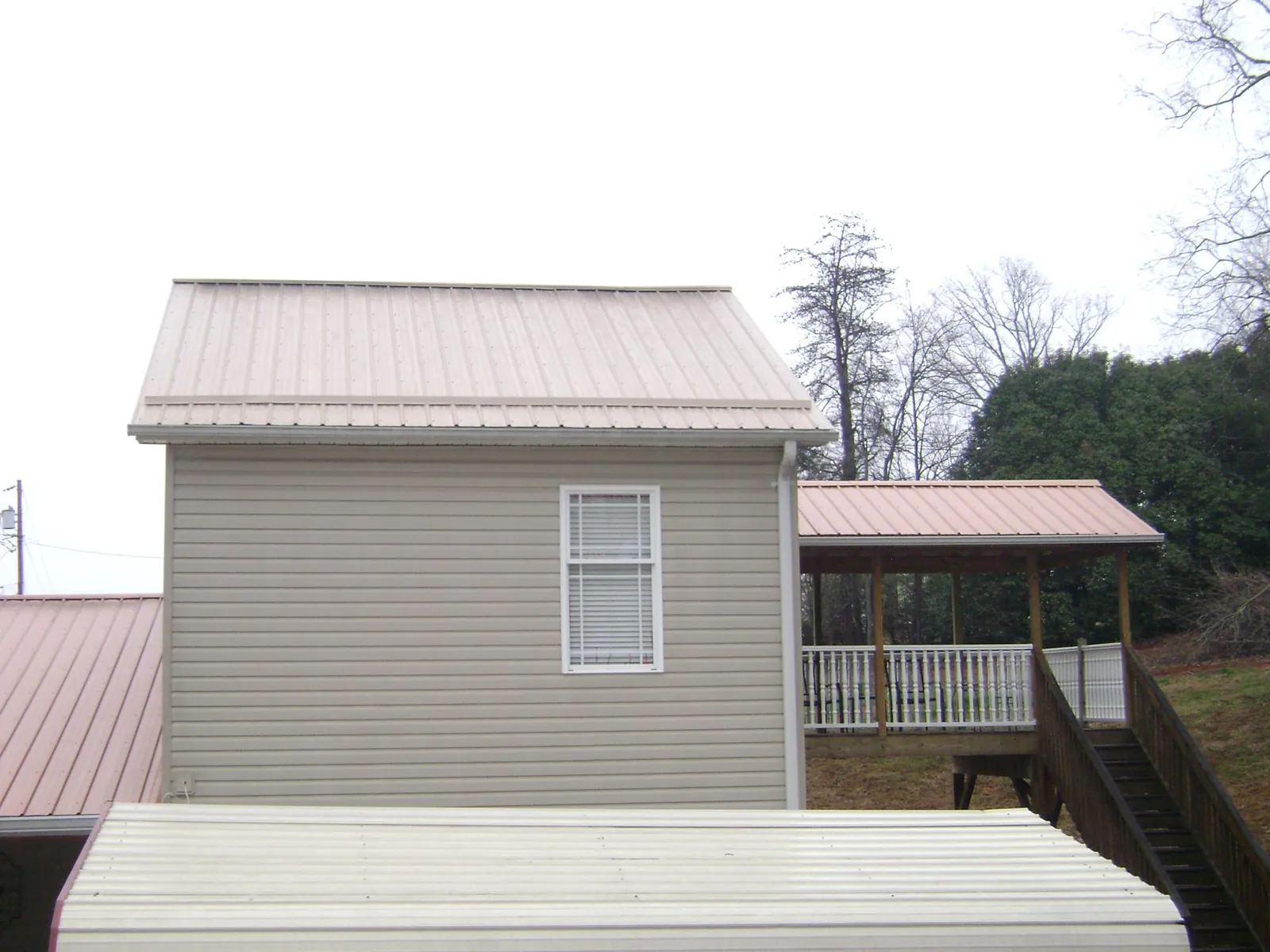 Tan metal roofs on a two story addition and attached porch, from a Roof Replacement job in Bellingham