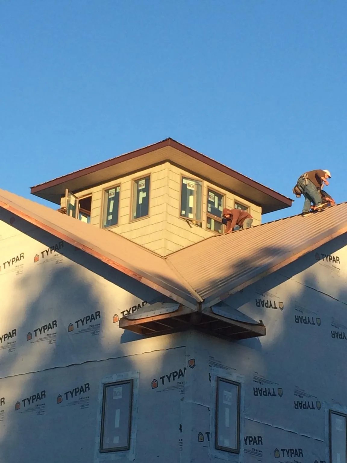 Roofers working around a rooftop cupola on a new metal roof at sunset — Roof Waterproofing in Bellingham by Roofing Brothers